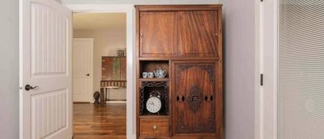 A hallway with a wooden cabinet, a white door, and a closed shutter.