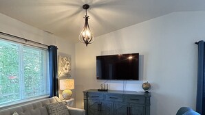 Una sala de estar con un sofá gris, un sofá azul, un aparador de madera y un televisor de pantalla plana montado en la pared.
