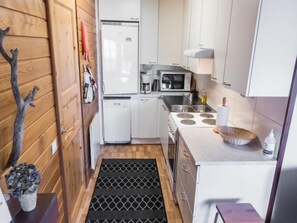 Compact kitchen with refrigerator, microwave, stove, sink, and countertop space.