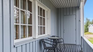 A covered porch with a table and two chairs, a window with blinds, and a door. - Saariseläntie 8 d7 by Interhome (Inari)