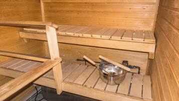 A sauna with wooden benches and a metal basin.