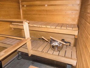 Un sauna avec des bancs en bois et un récipient en métal.