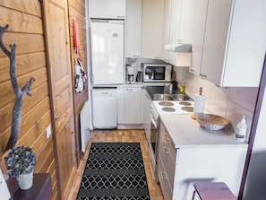 A compact kitchen with a refrigerator, microwave, stove, and sink.
