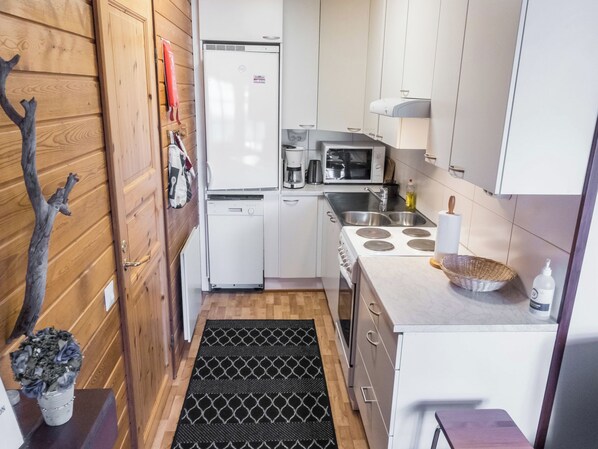 A compact kitchen with a refrigerator, microwave, stove, and sink.