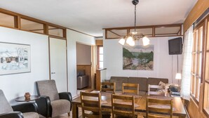 A dining area with a wooden table and chairs, a sofa, and a television. - Saariseläntie 8 d7 by Interhome (Inari)