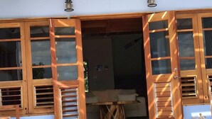 A wooden-framed entrance with open shutters, a table, and chairs outside.