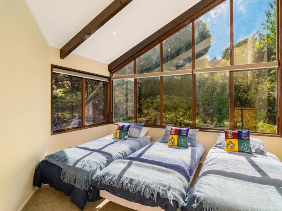 Une chambre avec deux lits, de grandes fenêtres et une vue sur la verdure.