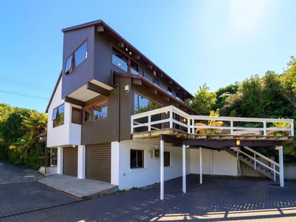 Une maison moderne à deux étages, dotée d’une allée couverte et d’une petite terrasse extérieure.