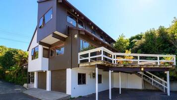 Une maison moderne à deux étages, dotée d’une allée couverte et d’une petite terrasse extérieure.