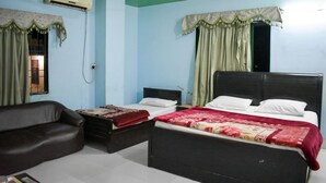 A bedroom with a bed, a chair, and an air conditioning unit. - New Capital Hotel (Lahore)