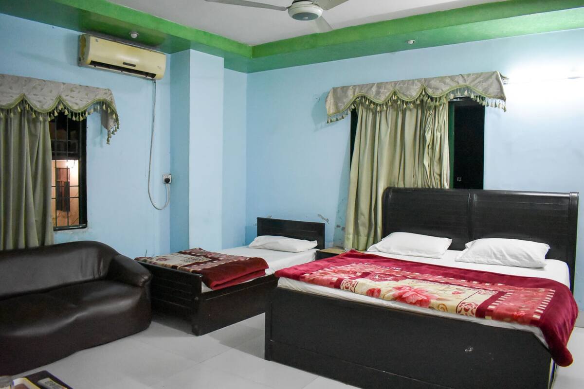 A bedroom with a bed, a chair, and an air conditioning unit.