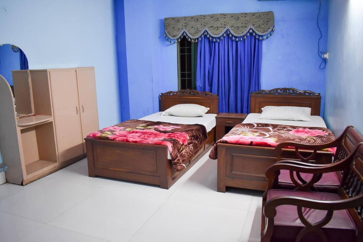 A bedroom with two wooden beds, a wardrobe, and a chair.