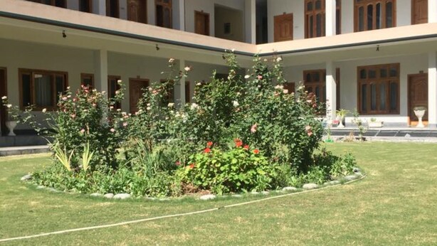 Une cour intérieure avec un jardin central, entourée d’un immeuble à plusieurs étages doté de balcons et de fenêtres.