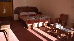 Une chambre avec un lit en bois, une chaise en bois, une petite table et une armoire.