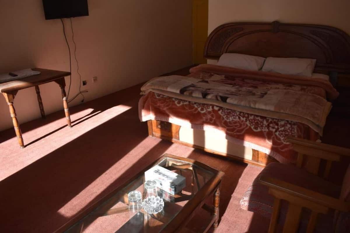 A bedroom with a bed, a bedside table, a glass coffee table, and a chair.