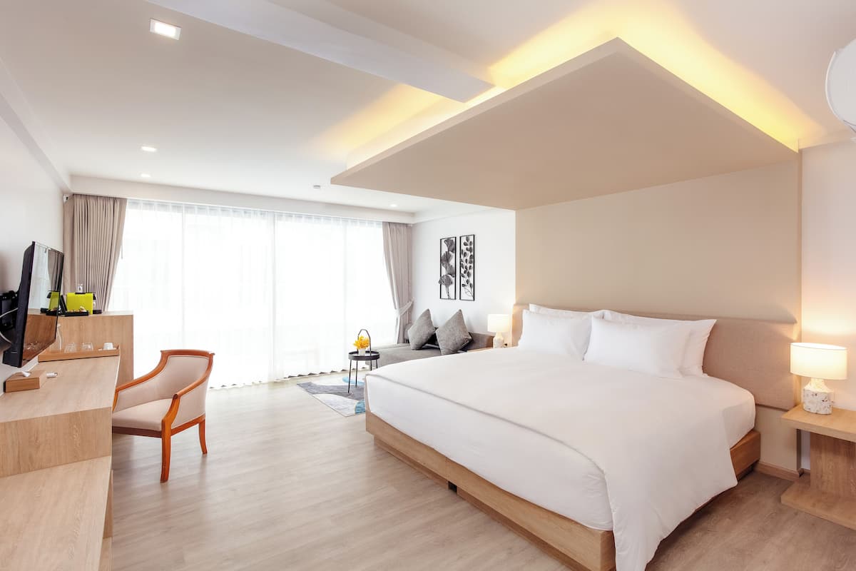 A modern hotel room with a large bed, a desk, a chair, and a TV.