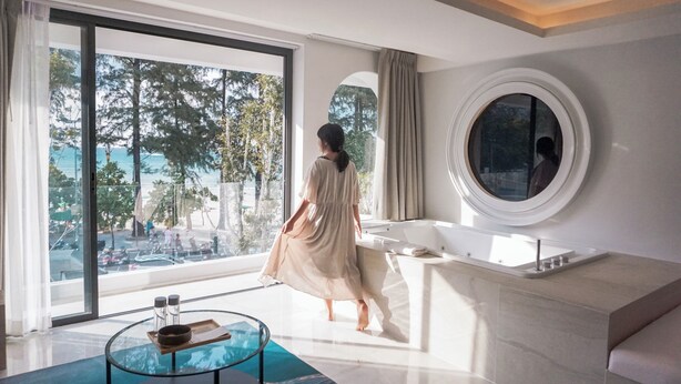 Un baño espacioso con un ventanal grande, un espejo redondo y una bañera.