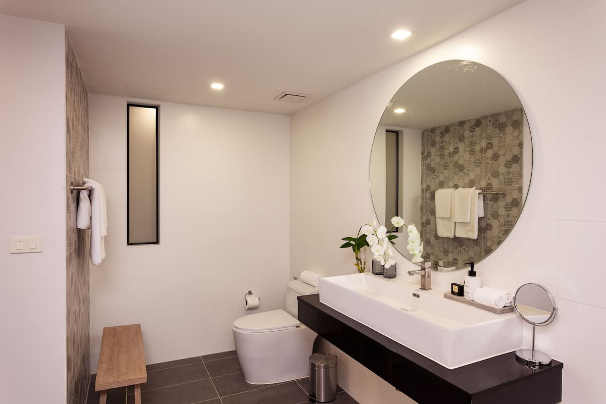 A modern bathroom with a white sink, a large mirror, and a toilet.