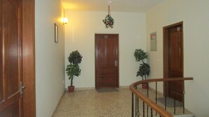 Um corredor com portas de madeira, escada com corrimão de madeira e plantas em vasos.
