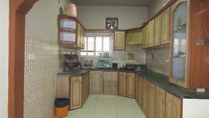 Cozinha com armários de madeira, pia e um relógio na parede.