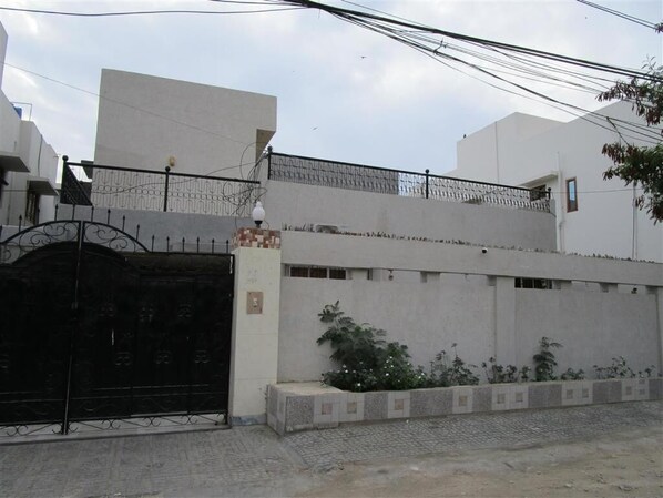 Un'area residenziale recintata con un muro in cemento, un cancello in metallo e un piccolo giardino.