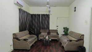 Sala de estar com dois sofás, uma mesa de centro, um ventilador de teto e uma porta.