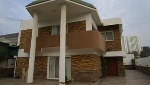 Um edifício moderno de dois andares com varanda, fachada de pedra e telhado plano.