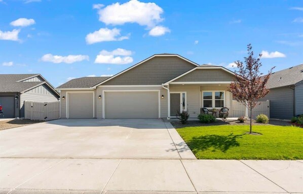 A single-story house with a garage, a covered front porch, and a small lawn.