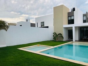 A modern house with a swimming pool, a well-maintained lawn, and a white exterior wall. - Fantastic modern House on Beautiful private community! (Mérida)