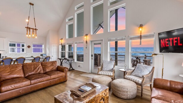 A spacious living room with a leather sofa, a coffee table, and a TV displaying 'NETFLIX'. - Beachfront | Pool | Ocean Views, Loft & Bar (Gilchrist)