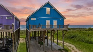 A beachfront property with two elevated houses, a deck, and a view of the ocean. - Beachfront | Pool | Ocean Views, Loft & Bar (Gilchrist)