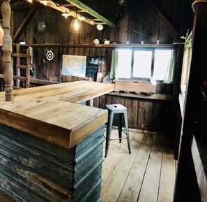 Um espaço de bar rústico com um balcão de madeira, um banquinho e um mapa na parede.