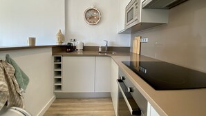 A modern kitchen with a clock, a microwave, and a coffee maker on the counter. - Perla del Mar - one step from the beach and center of Platja d'Aro (Castell-Platja d'Aro)