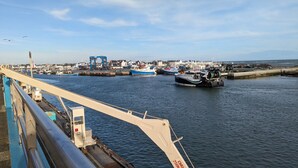 Een haven met boten, een havenkraan en een gebouw op de achtergrond.
