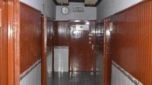 A hallway with wooden doors, a clock, and a tiled floor. - Davis Hotel (Lahore)