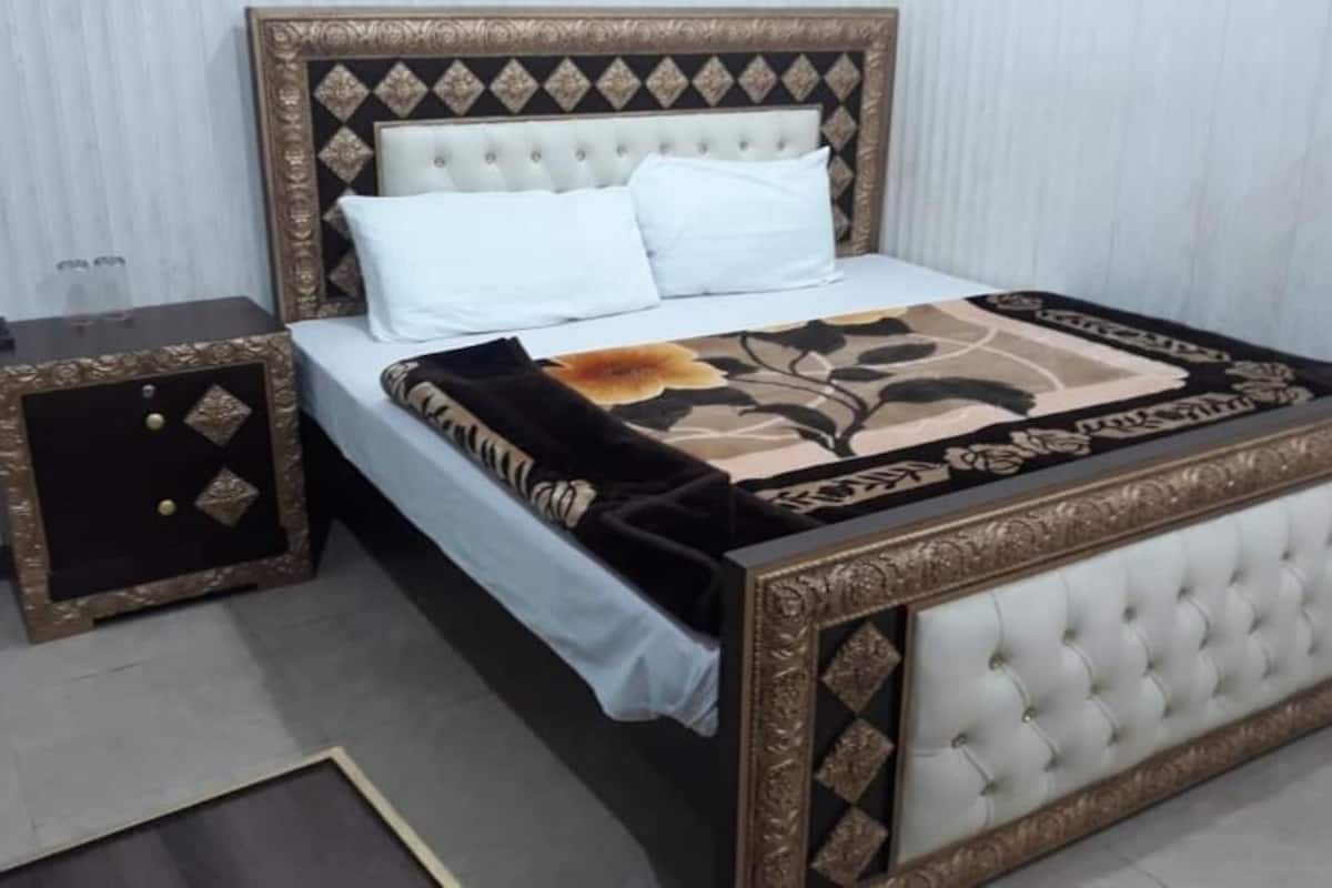A bedroom with a bed, nightstand, and a decorative headboard.