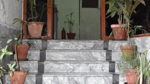 A set of marble steps leading to a door with a glass panel, flanked by potted plants. - Davis Hotel (Lahore)