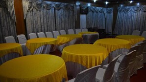 A banquet hall with round tables covered in yellow tablecloths and white chairs. - Gilgit Gateway Hotel (Gilgit)