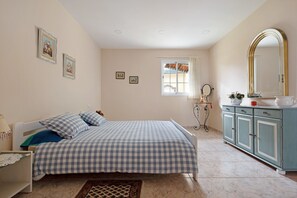 A bedroom with a bed, a dresser, a mirror, and framed pictures on the wall.