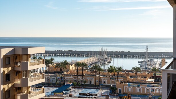 Un port de plaisance avec des bateaux, un immeuble doté de balcons et un ciel dégagé.