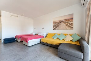 A room with a bed, two sofas, a small table, and a wall-mounted picture.