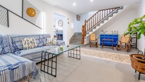 Un salon moderne avec un canapé, une table basse en verre et un escalier menant à un niveau supérieur.