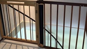 Uma escada com corrimão de madeira e uma luminária preta fixada na parede.