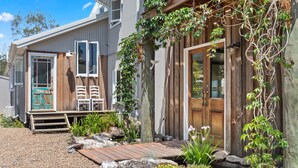 A rustic wooden house with a porch, a wooden deck, and a garden with plants and rocks. - Villa Sunshine - Pet Friendly Fully Air conditioned (Toogoom)