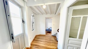 A hallway with wooden flooring, white walls, and a door with frosted glass panels.