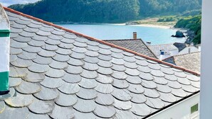 A coastal view with a tiled roof and a distant beach.
