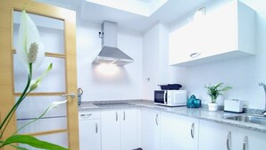 A modern kitchen with white cabinets, a stainless steel range hood, a microwave, and a sink. - The Cliffs - Sunset Village Beach 3E (Viveiro)