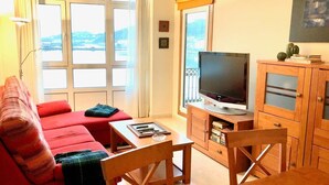A living room with a red sofa, wooden coffee table, and TV stand. - The Cliffs - Marina Sol te hará soñar (Viveiro)