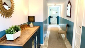 A hallway with a wooden bench, a white planter with greenery, and a mirror on the wall. - The Cliffs - Le Village Sarridal (Ortigueira)