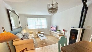 A living room with a sofa, a coffee table, a TV, a fireplace, and a chandelier. - The Cliffs - Le Village Sarridal (Ortigueira)